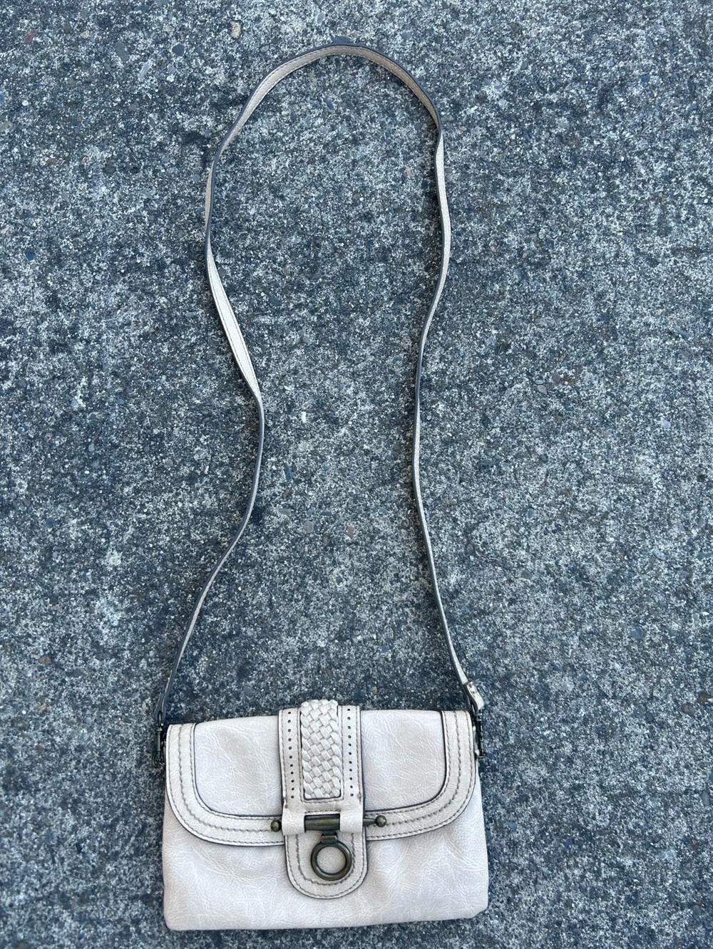 cream-colored leather crossbody purse with a thin shoulder strap